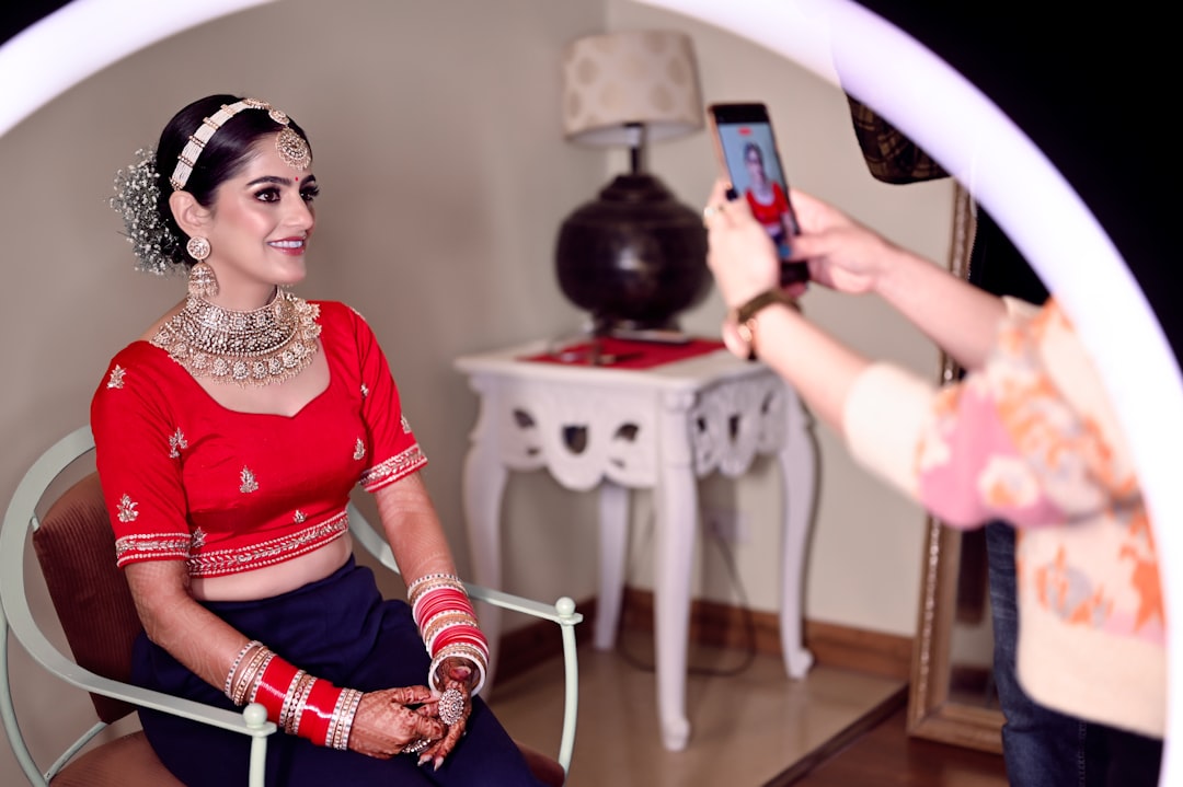 Professional bridal stylist working on bride's hair and makeup with traditional Indian jewelry and outfit preparations