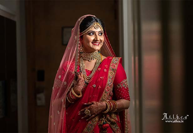 Bengali bride wearing traditional red saree and gold jewelry during wedding ceremony
