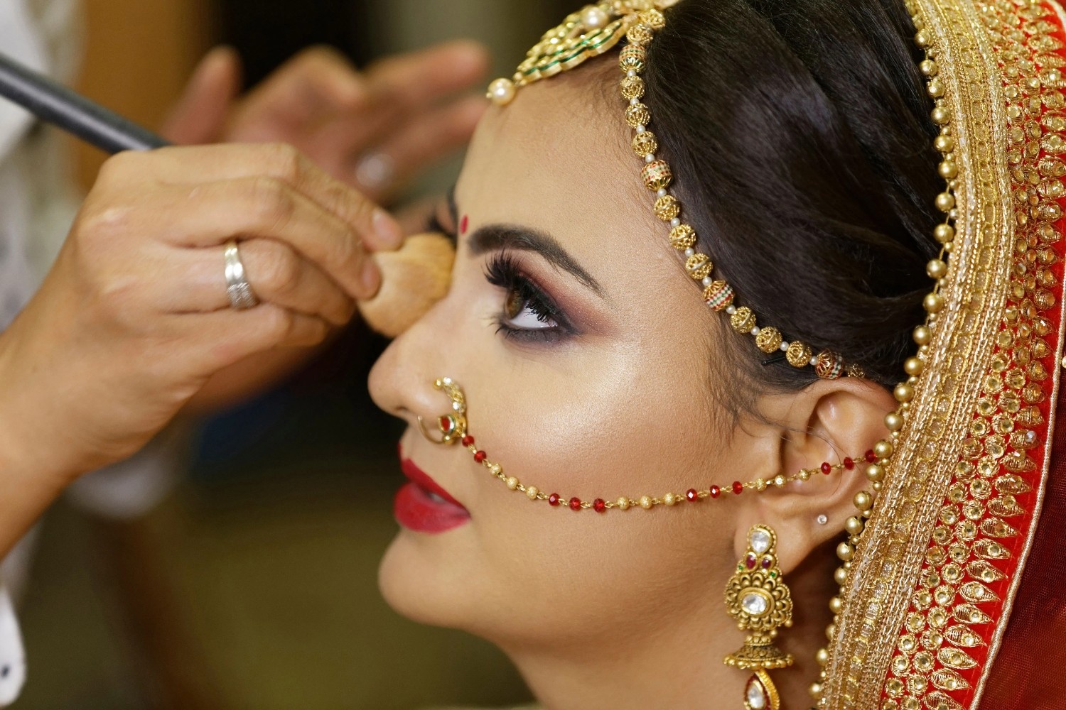 Beautiful Indian bride with long-lasting bridal makeup applying final touches