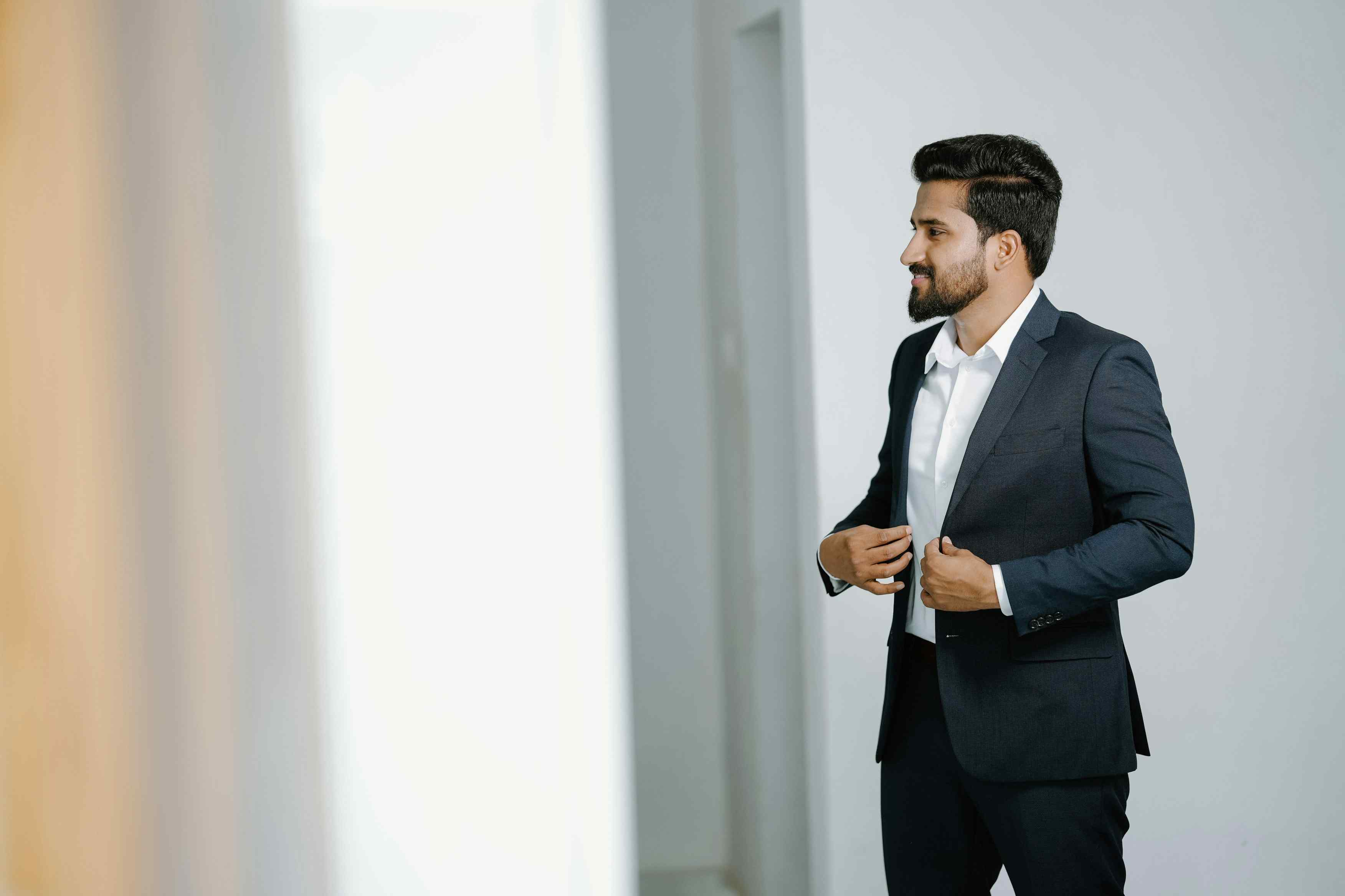 Groom practicing final grooming look in mirror before wedding