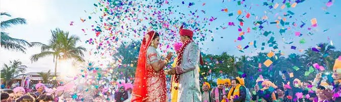 Luxury Confetti Setup Chennai — a bride and groom celebrating under a burst of gold and rose-petal confetti at a Chennai wedding reception