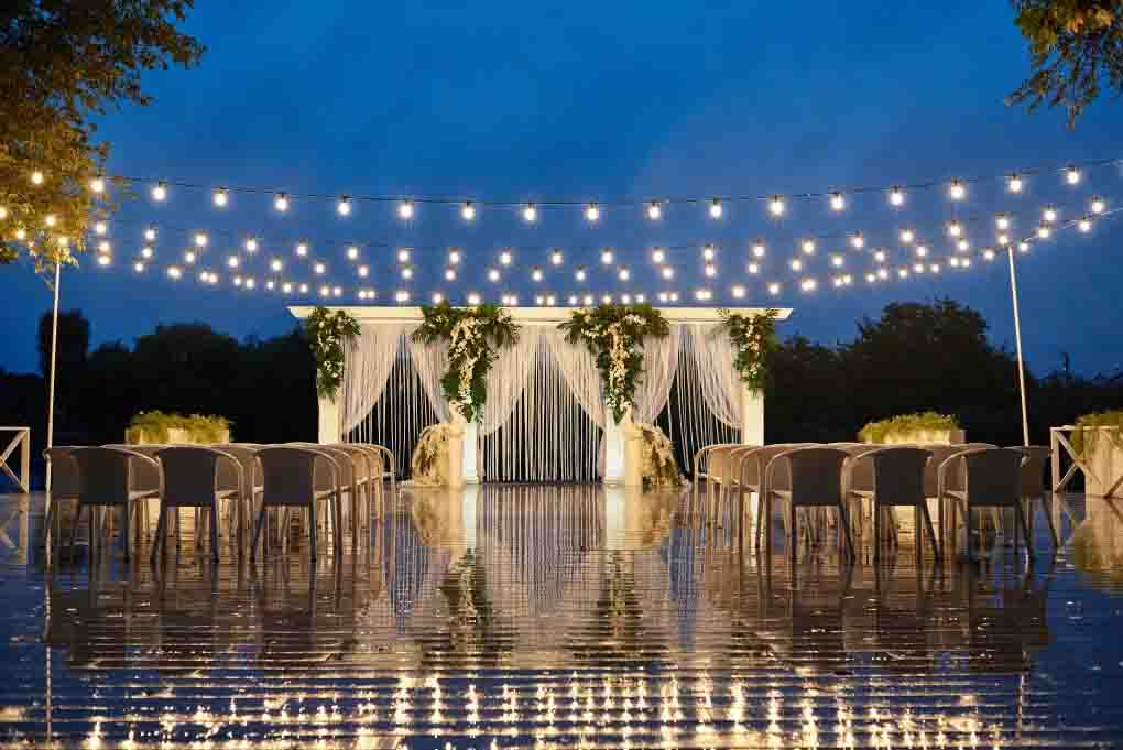 Elegant reception lighting Chennai setup with warm fairy lights and floral arch at a banquet hall