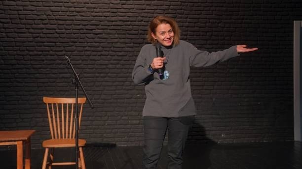 Corporate event with standup comedian performing on stage with engaged audience laughing