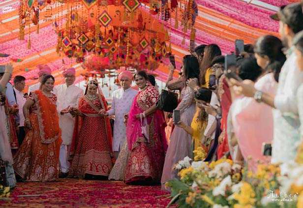 Vibrant wedding varmala stage decor with floral and colorful drapes